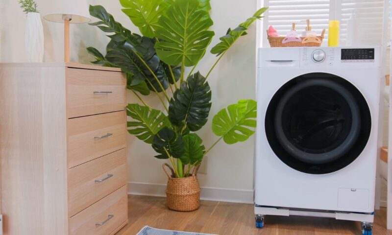 prikaz veš mašine u kupatilu pored police i biljke