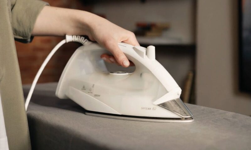 osoba drži peglu za peglanje u ruci