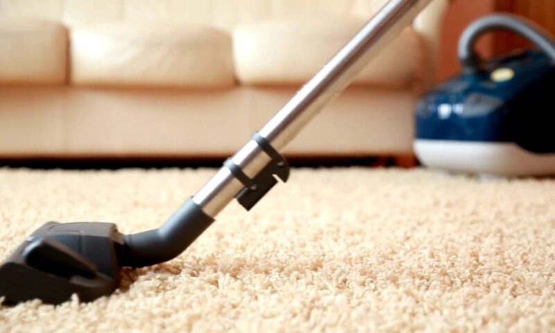 osoba usisava tepih sa usisivačem