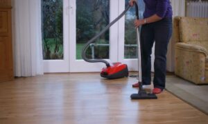 starija žena usisava parket sa crvenim usisivačem