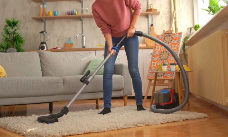 devojka usisava sa usisivačem koji ima posudu za prašinu